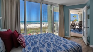 Ein Schlafzimmer mit einem großen Bett, Meerblick und einem Balkon mit Sitzgelegenheit.