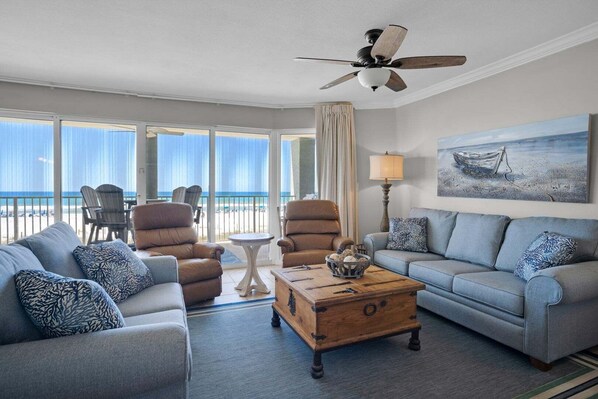 A room with a view of the beach, a ceiling fan, and a painting of a boat on the wall. - Tower 2-101, 3Bdr/3Bath, Low Floor, Beautiful Unit!!!  Sleeps 11!! FREE BEACH CHAIRS!! (Panama City Beach)