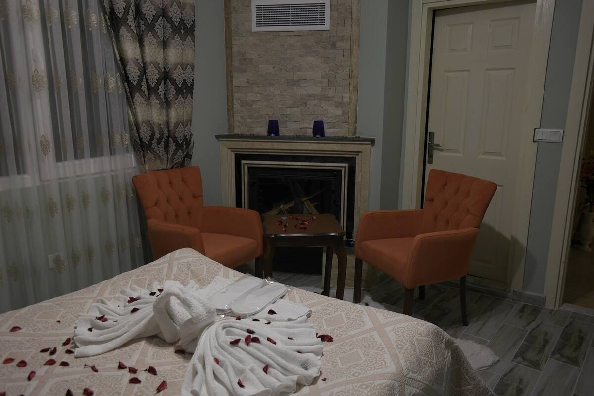 A room with a bed, two armchairs, a fireplace, and a door.