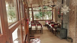 Un restaurant acollidor amb taules i seients de fusta, una paret de maó i un foc de llenya.