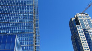 En modern skyskrapa med en fasad av glas och en byggkran i närheten.