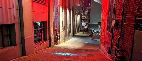 A narrow alleyway with a neon 'POST ALLEY' sign overhead.