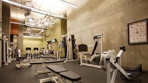 Ett gym med olika typer av träningsutrustning, inklusive löpband, styrketräningsmaskiner och träningsbänkar.