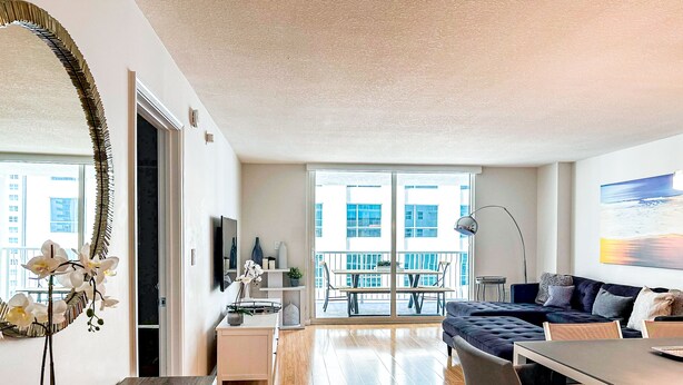 Un apartamento moderno con balcón, zona de comedor y sala de estar con sofá y televisor.