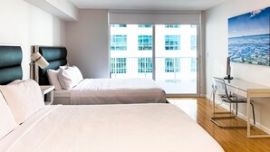 Un dormitorio moderno con una cama grande, una mesita de noche con lámpara, un escritorio con silla y un ventanal con vistas a la ciudad.