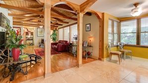 A spacious living area with wooden beams, a red leather sofa, and a dining table with chairs. - 5,000 sq. ft. Lake villa, 5/5 BA , sleeps 12,  2 boat stalls, 20x40 PRIVATE pool (Hot Springs)
