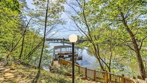 A wooden deck leading to a dock over water, surrounded by trees. - 5,000 sq. ft. Lake villa, 5/5 BA , sleeps 12,  2 boat stalls, 20x40 PRIVATE pool (Hot Springs)