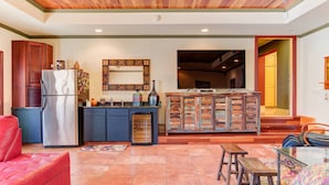 A spacious living area with a red sofa, a kitchen with a refrigerator and cabinets, a wooden cabinet with drawers, and a television. - 5,000 sq. ft. Lake villa, 5/5 BA , sleeps 12,  2 boat stalls, 20x40 PRIVATE pool (Hot Springs)