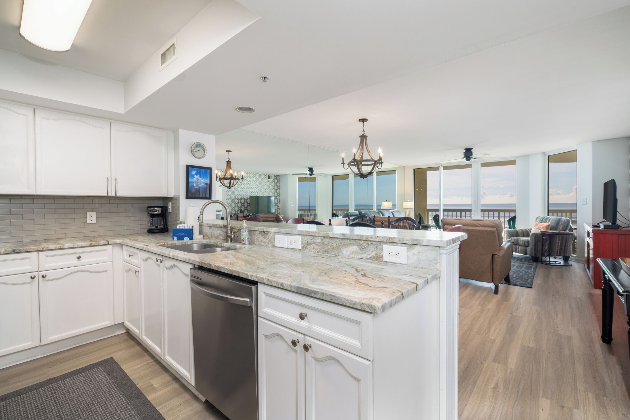 A spacious kitchen with a large island, white cabinetry, and a view of the ocean.