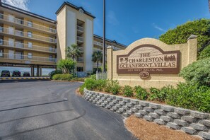 A sign for Charleston Oceanfront Villas with a multi-story building in the background.