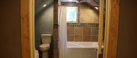 A bathroom with a bathtub, toilet, and shower curtain.