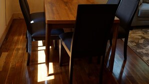 En matplats med ett träbord och fyra stolar, en spegel på väggen och ett fönster med utsikt över grönområden.