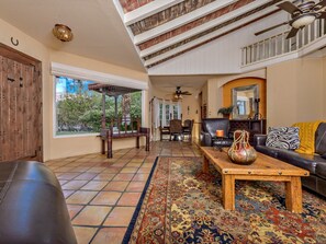 A spacious living area with a large window, a wooden coffee table, a leather sofa, and a patterned rug.