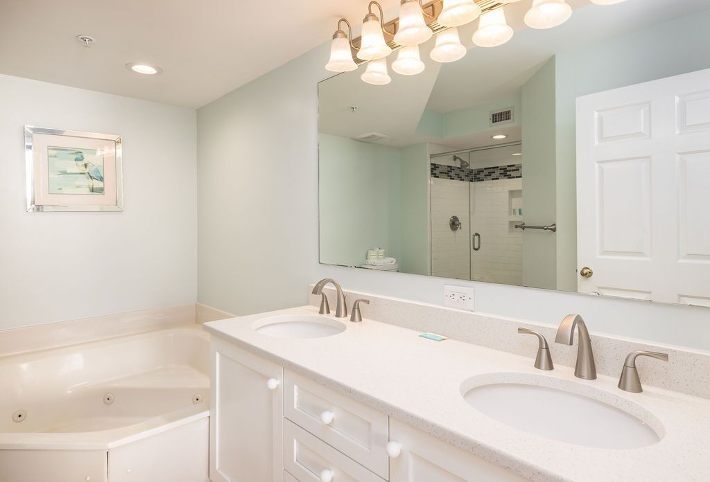 Une salle de bain avec deux lavabos, un grand miroir et une baignoire.