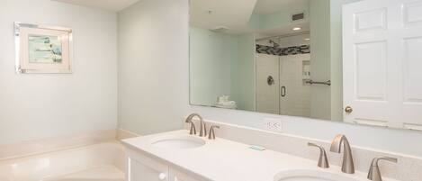 A bathroom with two sinks, a large mirror, and a bathtub.
