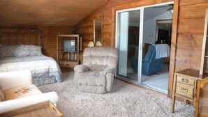 A cozy room with a bed, a chair, a small table, and a television.