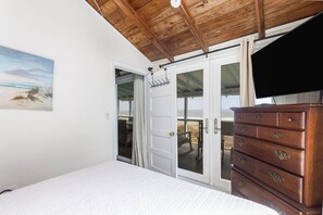 A bedroom with a bed, a wooden dresser, and a sliding glass door leading to a balcony.