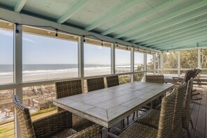 A covered outdoor seating area with a view of the beach.