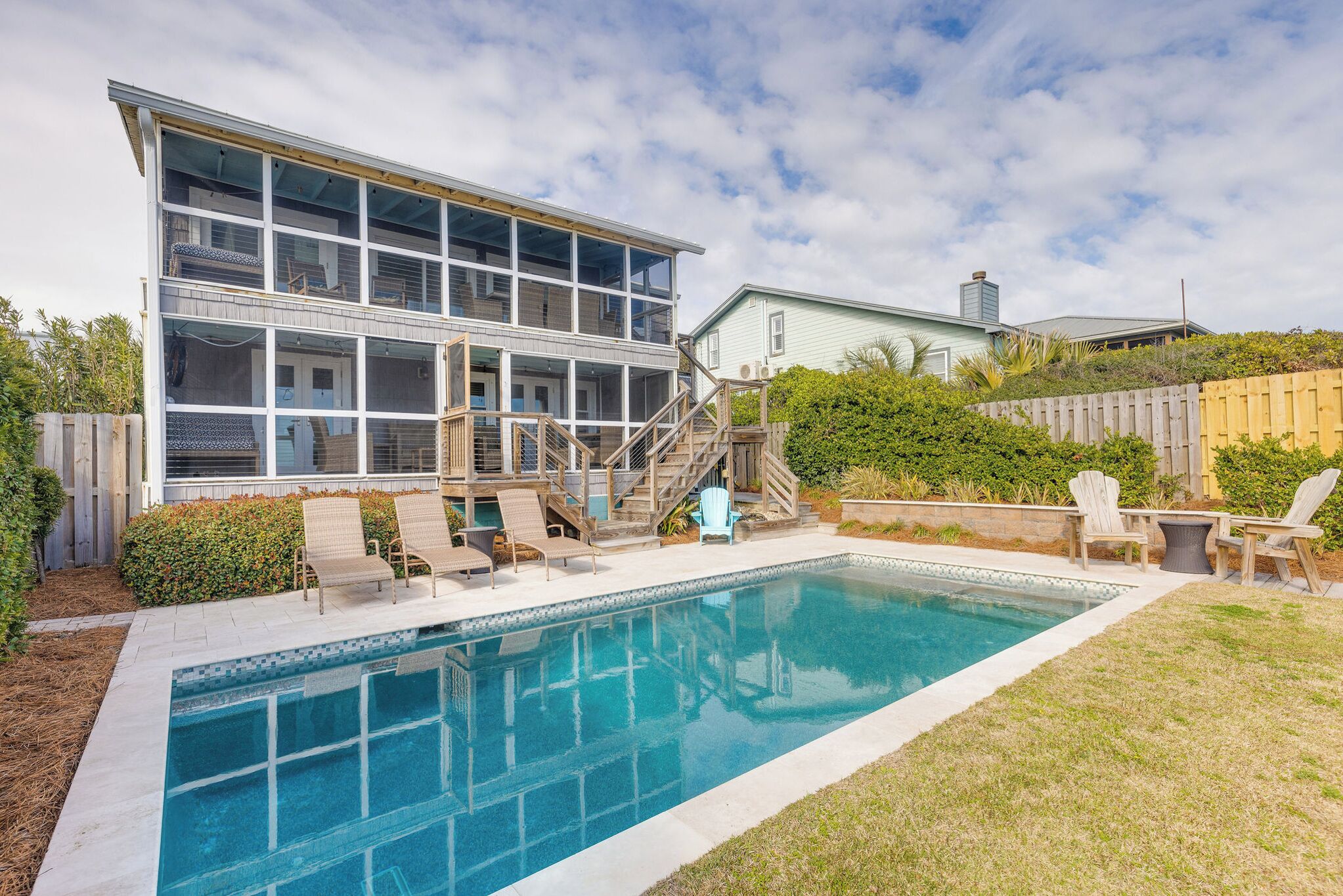 Une maison à deux étages avec une piscine, un espace salon extérieur et une terrasse en bois.
