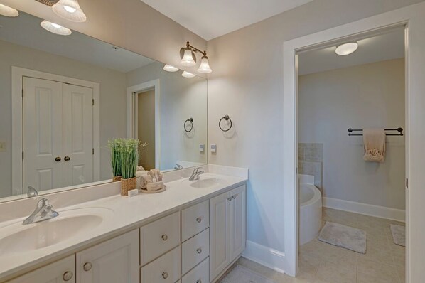 A bathroom with a double sink vanity, a large mirror, and a shower area.