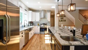 A modern kitchen with stainless steel appliances, a granite countertop, and a wooden floor.