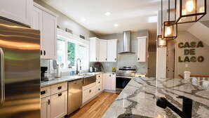 A modern kitchen with white cabinets, a stainless steel refrigerator, and a granite countertop.