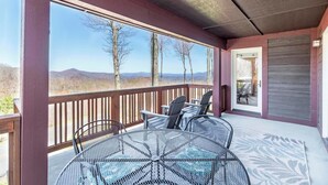 Un espace extérieur abrité, avec une table et des chaises, offrant une vue sur un paysage montagneux.