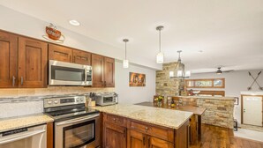 A modern kitchen with wooden cabinets, stainless steel appliances, and a granite countertop.