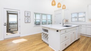 A modern kitchen with white cabinetry, a central island, and pendant lighting. - Stay @ Sea Cookie! Classic, Updated Beach Home (Folly Beach)
