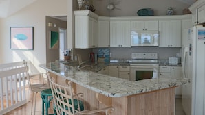A kitchen with white cabinets, a granite countertop, and a wooden island with bar stools.