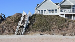 A beachfront property with a staircase leading to a multi-level building, surrounded by vegetation.
