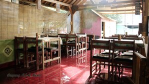 A restaurant with wooden tables and chairs, a tiled floor, and a wooden ceiling.