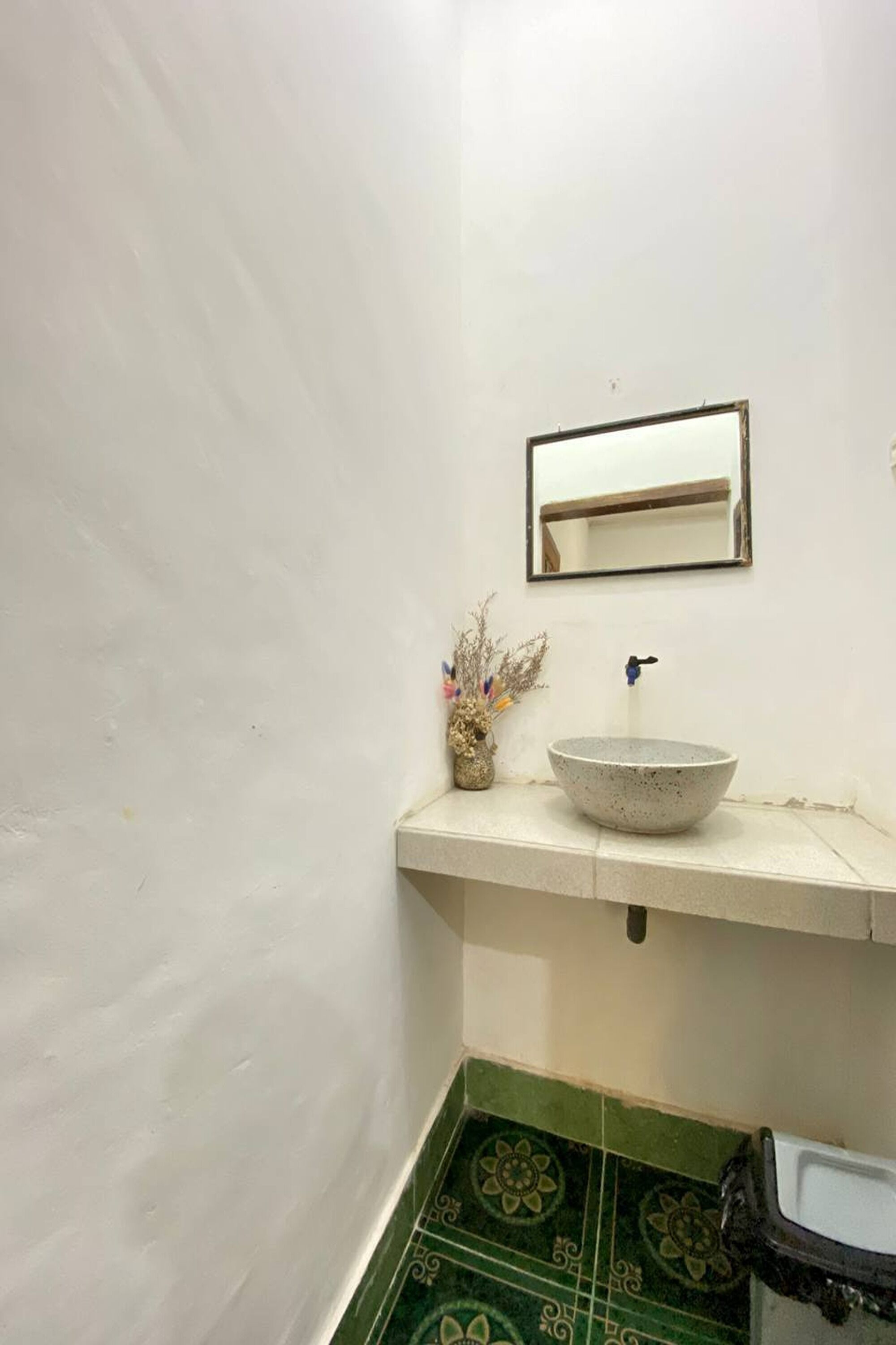 A bathroom with a white sink, a mirror, and a green patterned floor.