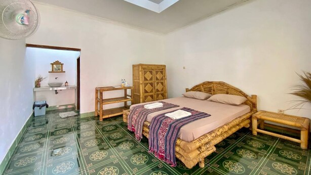 A bedroom with a bed, bedside tables, a wardrobe, and a bathroom visible through an open doorway.