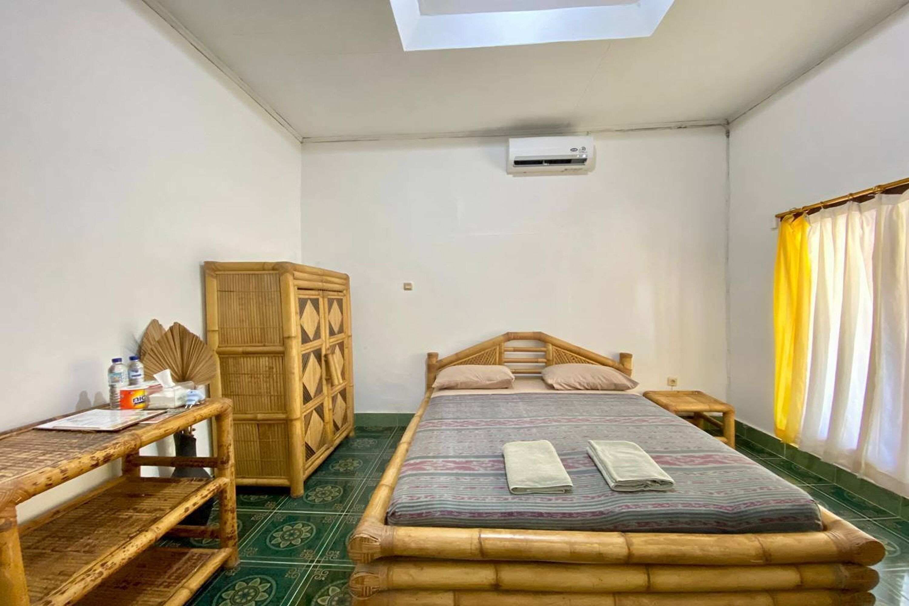 A room with a bed, a wooden desk, a wardrobe, and a window with curtains.