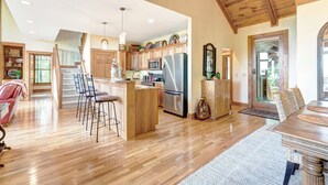 Una cocina amplia con armarios de madera, un refrigerador de acero inoxidable y una barra con taburetes.