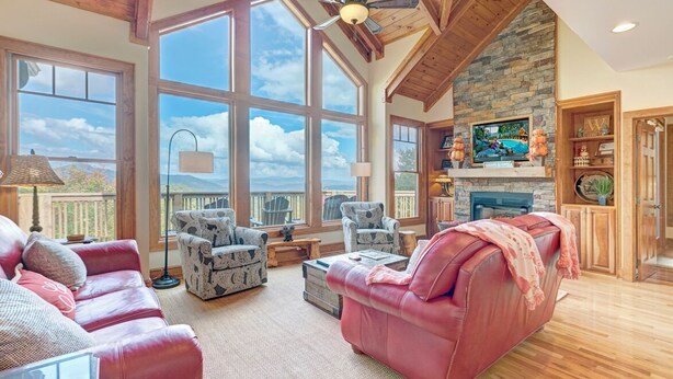 Un salón amplio con ventanas grandes, chimenea y una pared de acento de piedra.