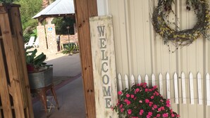 A welcome sign, a metal bucket, and a potted plant on a porch.