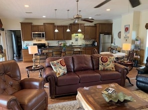 Relax in this stylish living area with a modern kitchen, featuring a comfortable sofa, armchair, and coffee table.