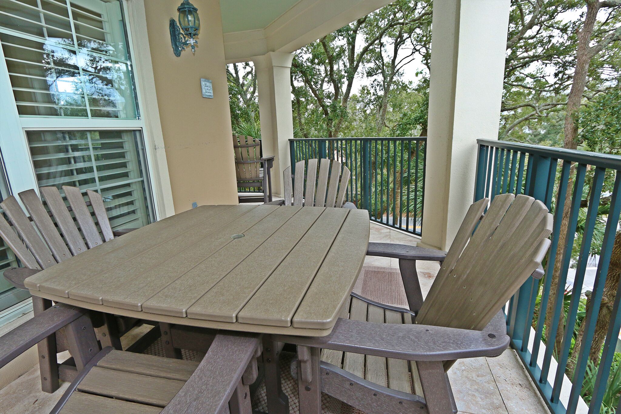 A covered outdoor patio with a wooden table and chairs, surrounded by a railing.
