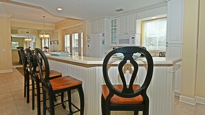 A kitchen with a central island, bar stools, and a microwave. - 301 North Shore End Unit, No carpet, CLEAN, Wrap-around Balcony, August Avail. (Hilton Head Island)