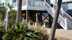 A two-story building with a white balcony railing, a covered walkway, and palm trees in the foreground. - AT THE BEACH!  Beautiful 3 Bed and 3 Bath (Gulf Shores)