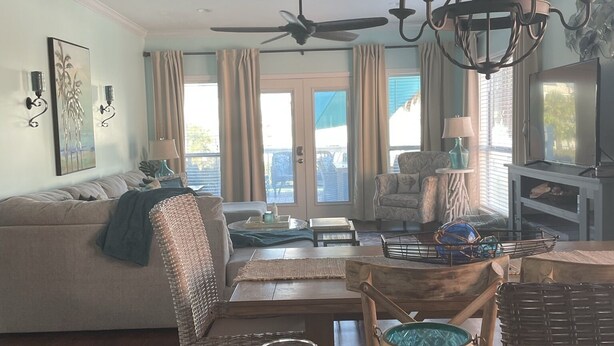 A cozy living room with a sofa, a dining table with a wine glass, and a chandelier. - AT THE BEACH!  Beautiful 3 Bed and 3 Bath (Gulf Shores)