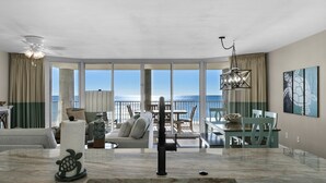 Un vaste espace de vie avec une grande fenêtre donnant sur la mer, un coin repas avec vue et un ventilateur de plafond.