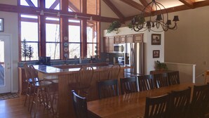 A spacious kitchen with a large island, wooden ceiling beams, and a dining area with multiple chairs.