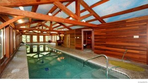 Une cabane en bois dotée d’une piscine, de grandes fenêtres et d’un intérieur rustique.