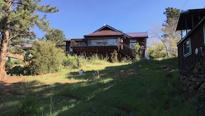 A two-story wooden house with a metal roof, surrounded by grass and trees. - Family Friendly, Close To Downtown, Best views of Longs Peak and the Range (Estes Park)