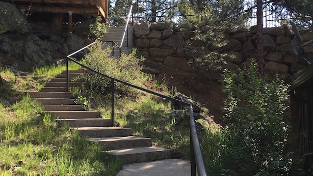 A concrete pathway with metal railings leading up a stone wall, surrounded by greenery and trees. - Family Friendly, Close To Downtown, Best views of Longs Peak and the Range (Estes Park)