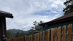 A hot tub with a wooden fence and mountains in the background. - Family Friendly, Close To Downtown, Best views of Longs Peak and the Range (Estes Park)