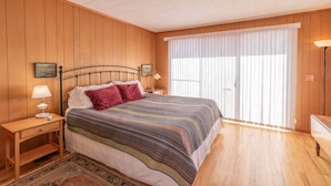 A bedroom with a bed, two bedside tables, a nightstand, a lamp, a window with blinds, and a wooden floor. - Family Friendly, Close To Downtown, Best views of Longs Peak and the Range (Estes Park)